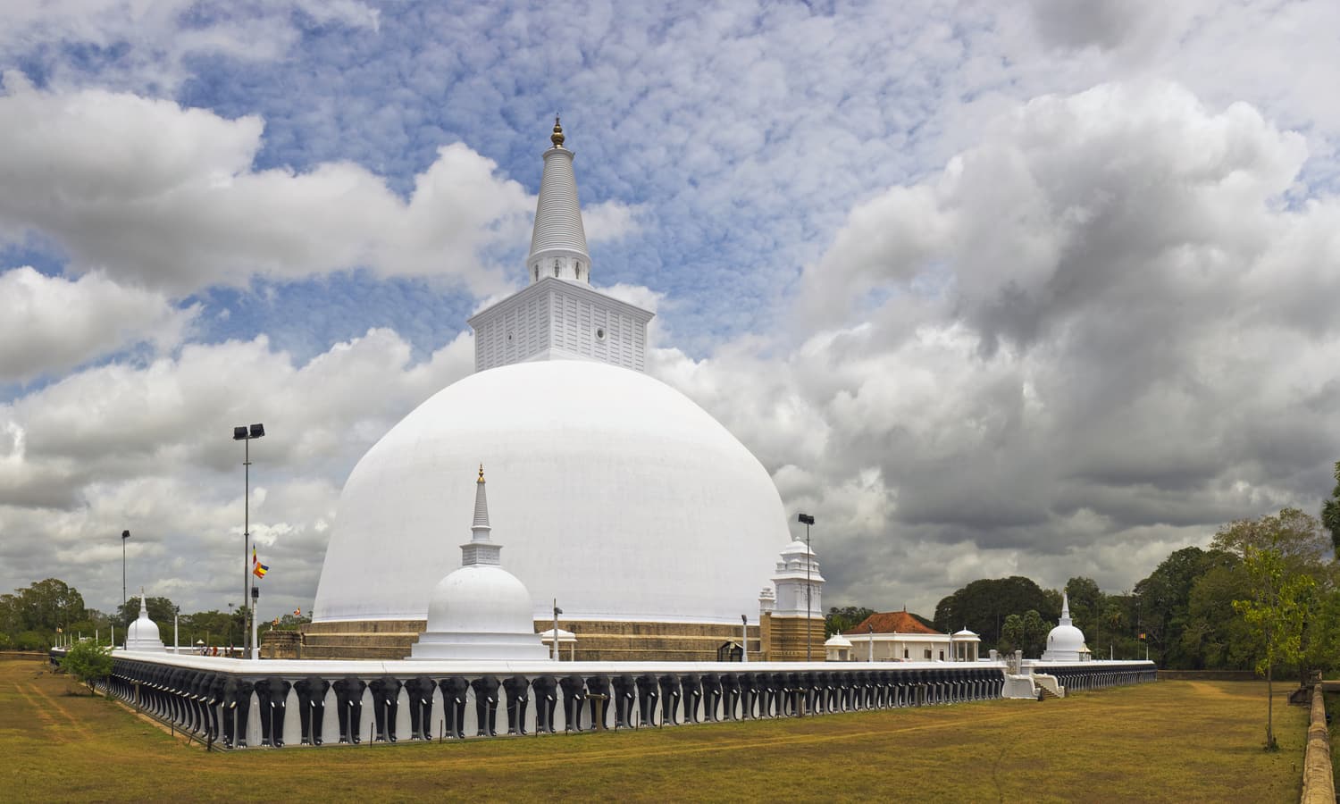 The white dome of the Ruwanwelisaya stupa in Anuradhapura under a cloudy sky