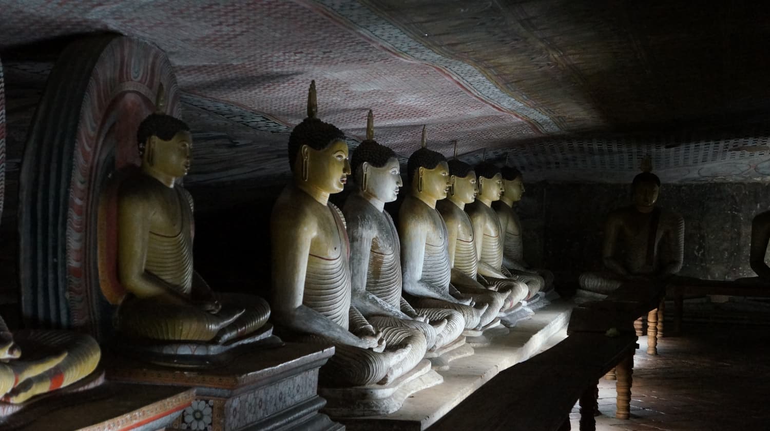 Rows of seated Buddha statues inside a Dambulla cave shrine